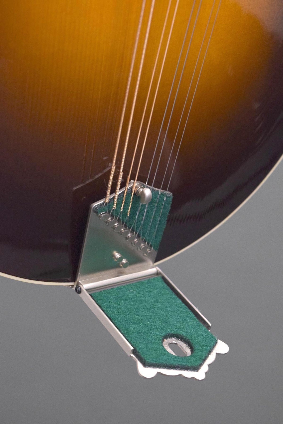 Big Mon tailpiece with the cover lifted, showing the string anchors and green felt