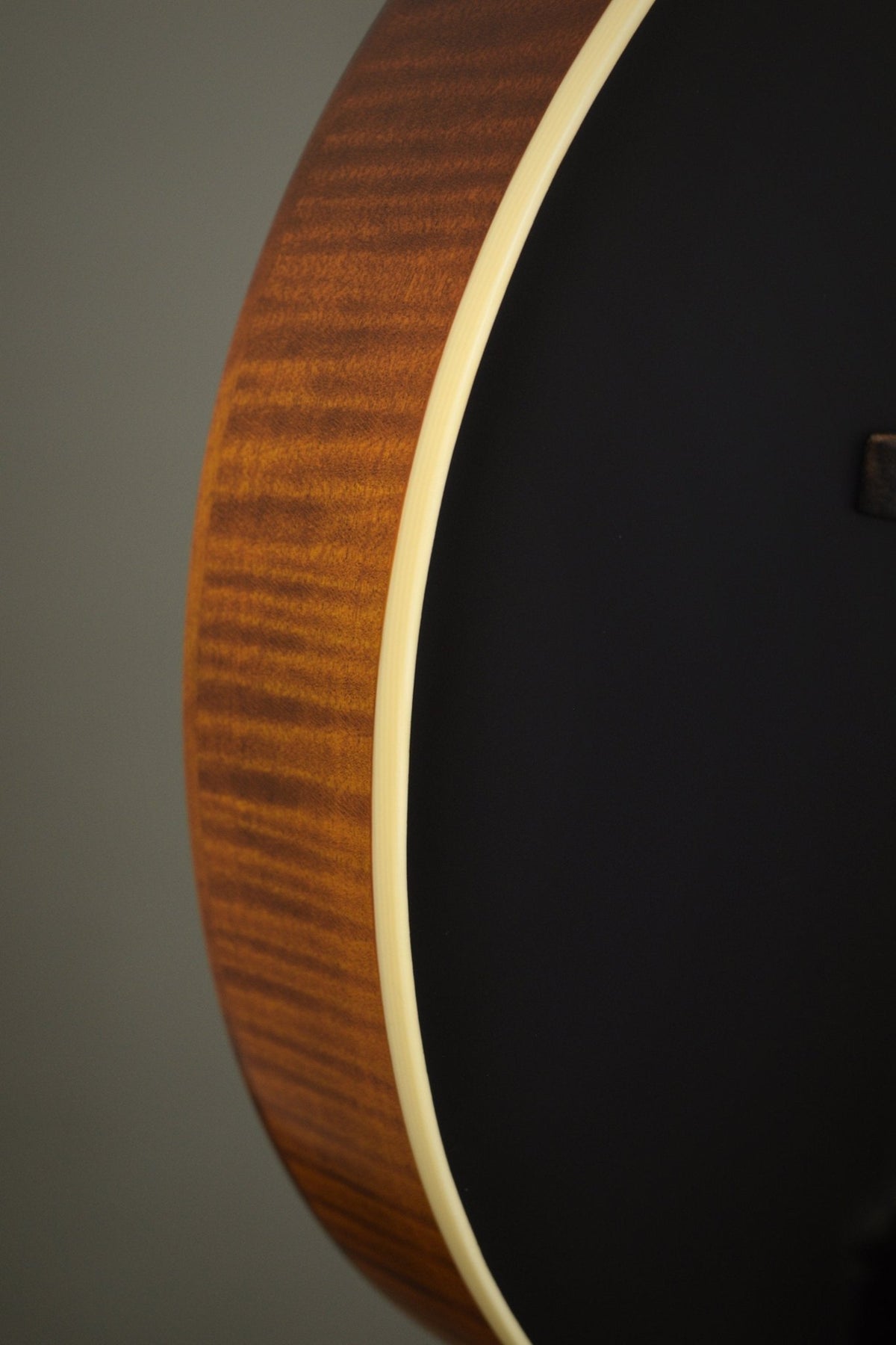 Flame maple rim and ivoroid binding along the F2S mandolin's black top edge