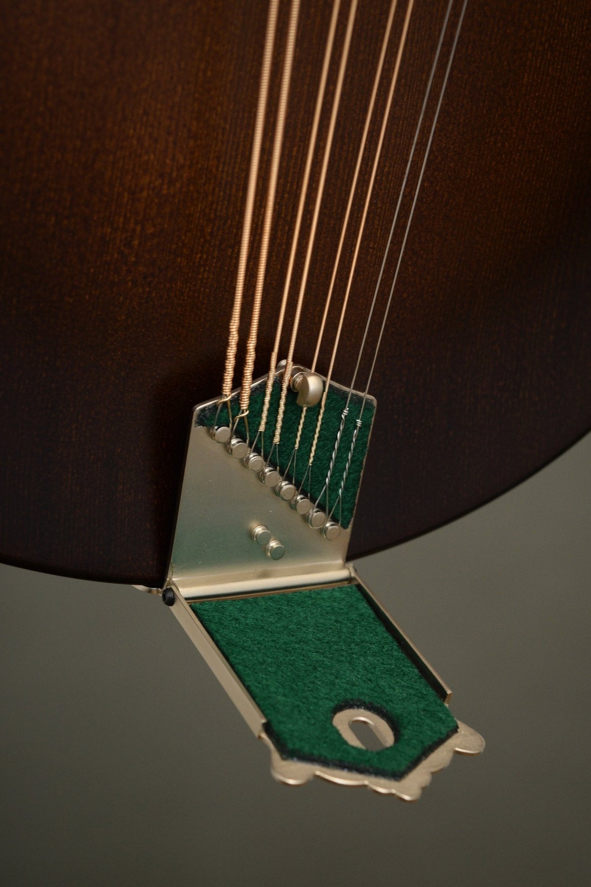 Wavelength tailpiece with the cover lifted, showing the string anchors and green felt